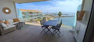 a balcony with a table and chairs and the ocean at NEPITA- Vue mer- piscine en résidence de standing- clim-Wifi in Sari Solenzara