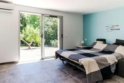 a bedroom with a bed and a large window at Studio en pierre U Pinu, 2 personnes, Muratello, 6 Kms de Porto Vecchio in Porto-Vecchio
