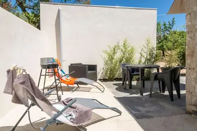 a patio with chairs and tables on a wall at Studio en pierre U Pinu, 2 personnes, Muratello, 6 Kms de Porto Vecchio in Porto-Vecchio
