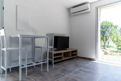 a living room with a television and a window at Studio en pierre U Pinu, 2 personnes, Muratello, 6 Kms de Porto Vecchio in Porto-Vecchio
