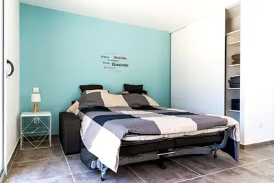 a bedroom with a bed with a blue wall at Studio en pierre U Pinu, 2 personnes, Muratello, 6 Kms de Porto Vecchio in Porto-Vecchio