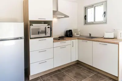 a kitchen with white cabinets and a microwave at Studio en pierre U Pinu, 2 personnes, Muratello, 6 Kms de Porto Vecchio in Porto-Vecchio