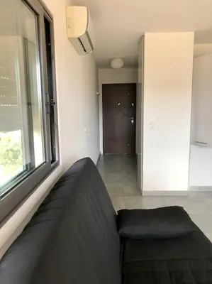 a living room with a couch and a window at Studio Piscine, 200m port de Porto Vecchio pour 2 personnes in Porto-Vecchio