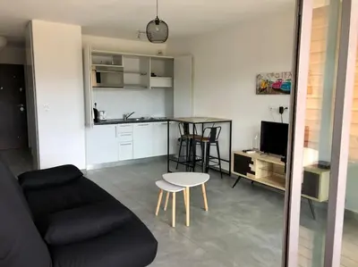 a living room with a couch and a table and a kitchen at Studio Piscine, 200m port de Porto Vecchio pour 2 personnes in Porto-Vecchio
