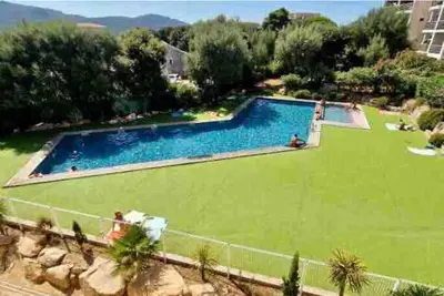 a large swimming pool with a green lawn at Studio Piscine, 200m port de Porto Vecchio pour 2 personnes in Porto-Vecchio