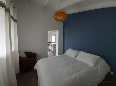 a bedroom with a white bed and a blue wall at Le nid d'Aigle - proche Ajaccio in Cuttoli-Corticchiato
