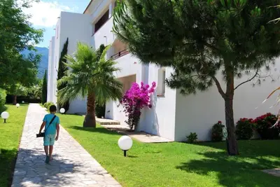 a person walking down a path in front of a building at Appt dans résidence avec piscines et plage privées in San-Nicolao