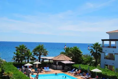 a resort with a swimming pool next to the ocean at Appt dans résidence avec piscines et plage privées in San-Nicolao