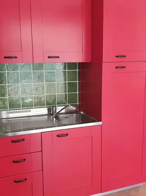 a red kitchen with a sink and red cabinets at Appt dans résidence avec piscines et plage privées in San-Nicolao