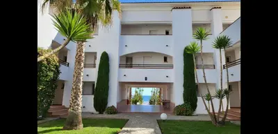 a large white building with palm trees in front of it at Appt dans résidence avec piscines et plage privées in San-Nicolao