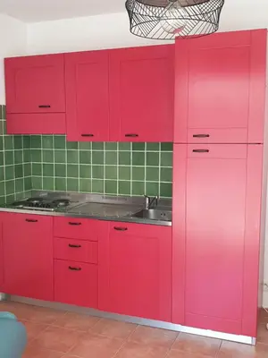 a red kitchen with a sink and red cabinets at Appt dans résidence avec piscines et plage privées in San-Nicolao