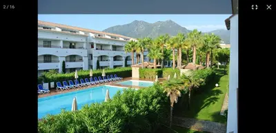 a view of a hotel with a swimming pool and palm trees at Appt dans résidence avec piscines et plage privées in San-Nicolao