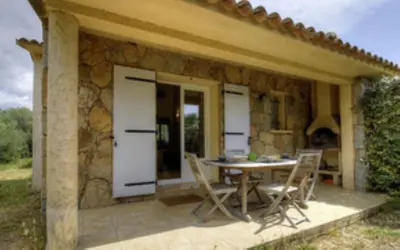 a stone house with a table and chairs on a patio at Les bergeries d'Ogliastrello in Figari