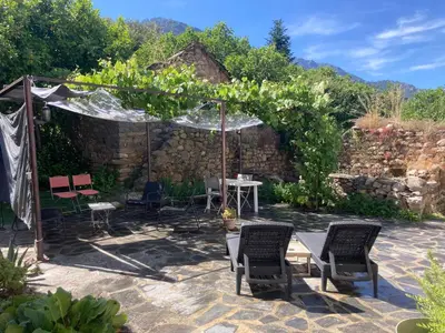 a patio with chairs and a table in a garden at Maison Kyprea: charmant appartement /duplex , spacieux, tout confort avec terrasse extérieure privée, parking privatif , vue pittoresque sur la citadelle de Corté et les montagnes. in Corte