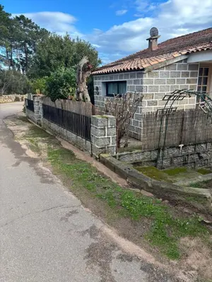 a brick house with a fence next to a street at Maison de village en granite in Porto-Vecchio