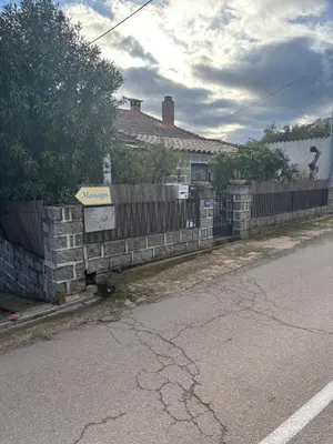 a fence on the side of a road next to a house at Maison de village en granite in Porto-Vecchio