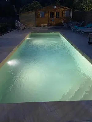 a large swimming pool with blue water at night at Maison de village en granite in Porto-Vecchio