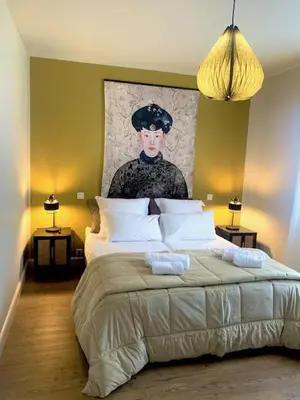 a bedroom with a large bed with a painting on the wall at A CASA DI MAMMA in Pianottoli-Caldarello