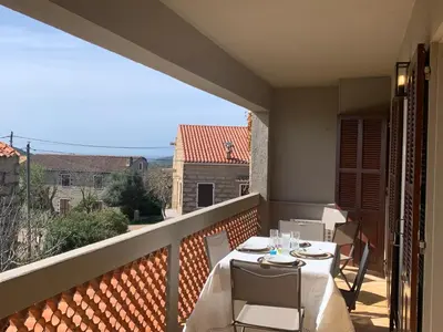 a balcony with a table and chairs with a view at A CASA DI MAMMA in Pianottoli-Caldarello