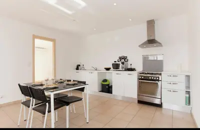 a white kitchen with a table and chairs at Chez telou in Borgo