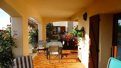 a patio with a table and chairs and flowers at Amon nos Ôtes in Vezzani
