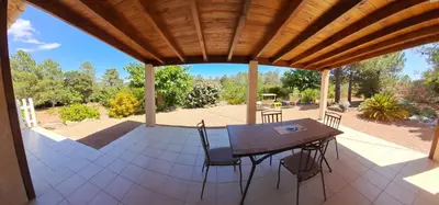 a patio with a table and chairs under a wooden roof at Villa avec piscine hors sol à 10mn de la plage in Lecci