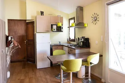 a kitchen with a wooden table and yellow chairs at Studio Indépendant avec Terrasse in Furiani