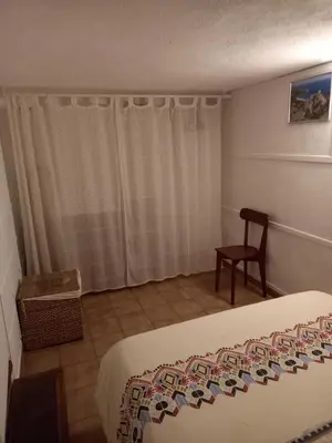 a bedroom with a bed and a chair and a window at appartement climatisé 35 m2 pour 1 couple - piscine partagée - in Porto-Vecchio