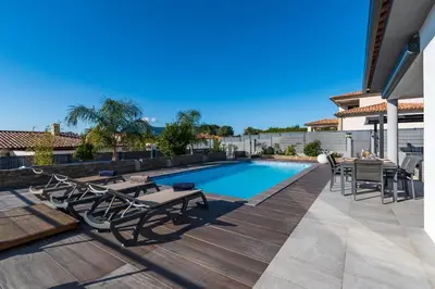 a swimming pool with tables and chairs on a deck at Afa, proche d Ajaccio, Magnifique Villa 4 pers avec Piscine privée et vue montagne in Afa