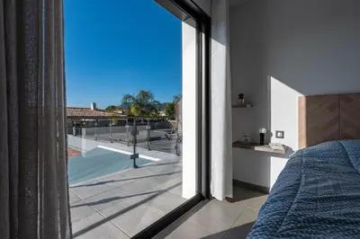 a bedroom with a bed and a view of a balcony at Afa, proche d Ajaccio, Magnifique Villa 4 pers avec Piscine privée et vue montagne in Afa