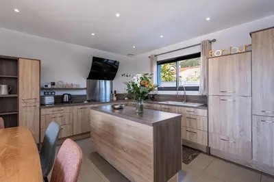 a kitchen with wooden cabinets and a vase of flowers on a counter at Afa, proche d Ajaccio, Magnifique Villa 4 pers avec Piscine privée et vue montagne in Afa