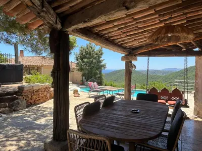 a wooden table and chairs under a wooden pergola at Villa CAROLE Piscine privée Spa Fautéa in Zonza