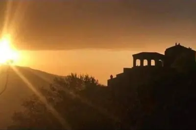 a sunset with the sun setting behind a building at Maison Lama in Lama