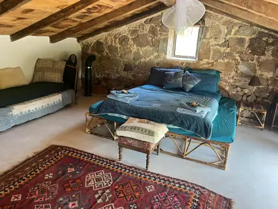a bedroom with a bed and a couch and a rug at Maison typique Corse écologique in Coti-Chiavari