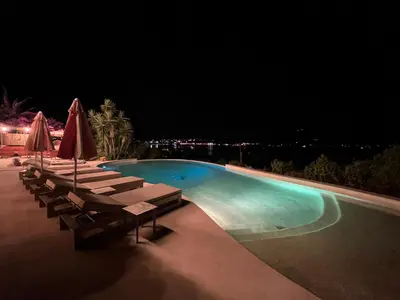 a swimming pool at night with chairs and umbrellas at Hotel Riva Beach in Porto-Vecchio