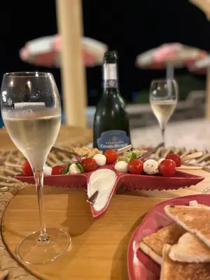a table with two glasses of wine and a tray of food at Hotel Riva Beach in Porto-Vecchio