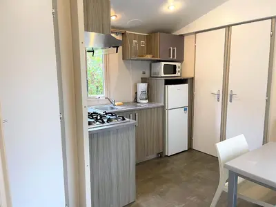 a kitchen with wooden cabinets and a white refrigerator at Camping Olva *** in Sartène