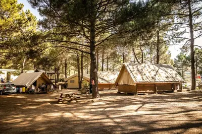 a bedroom with a bed and a window with curtains at Camping Olva *** in Sartène