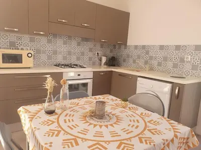 a kitchen with a table with a table cloth on it at Studio mitoyen à la campagne vue sur la mer in Cargèse
