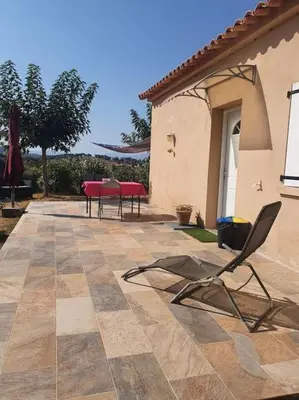 a patio with a table and chairs in a house at Studio mitoyen à la campagne vue sur la mer in Cargèse