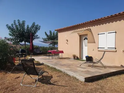 a group of chairs sitting on a patio next to a house at Studio mitoyen à la campagne vue sur la mer in Cargèse