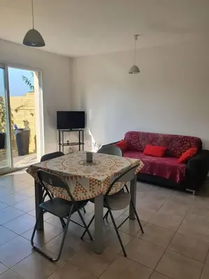 a living room with a table and a red couch at Studio mitoyen à la campagne vue sur la mer in Cargèse