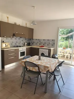 a kitchen with a table and chairs in a kitchen at Studio mitoyen à la campagne vue sur la mer in Cargèse
