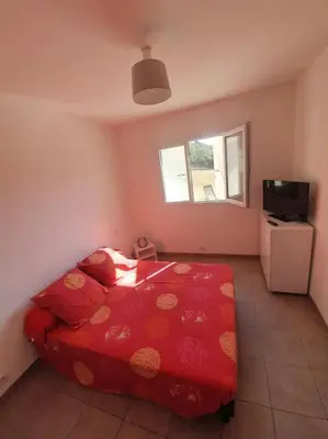 a bedroom with a red bed and a television at Studio mitoyen à la campagne vue sur la mer in Cargèse