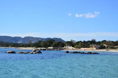 a man sitting on rocks in the water at ST CYPRIEN D29 -4/5 pers- à 250m de la plage de sable Saint Cyprien in Lecci