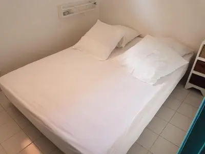a large white bed with two pillows on it at ST CYPRIEN D29 -4/5 pers- à 250m de la plage de sable Saint Cyprien in Lecci