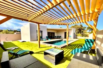 a backyard with a swimming pool and a wooden pergola at VILLA LE CORAIL ROUGE CORSE in Lecci