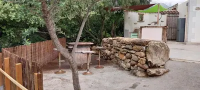 a stone wall next to a building with a green umbrella at Villa A Volta in Urtaca