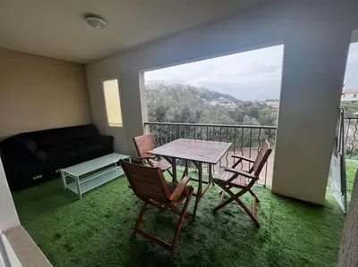 a balcony with a table and chairs and a couch at Trés Bel appartement de 105 M2 et 45 M2 de terrasse à 100 m du port in Porto-Vecchio