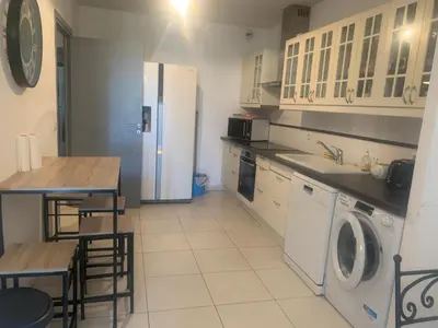 a kitchen with a refrigerator and a table and a washer at Trés Bel appartement de 105 M2 et 45 M2 de terrasse à 100 m du port in Porto-Vecchio
